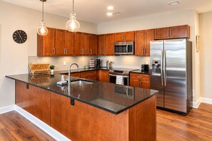 A modern kitchen with wooden cabinets, stainless steel appliances, a large island with a sink, and pendant lighting. - Terminal Tower - Spacious! RnRHoF, Casino, Stadium (Cleveland)