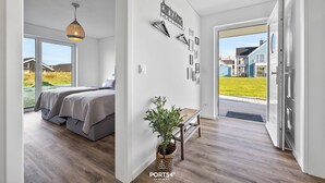 A modern bedroom with a large bed, a hanging light fixture, and a view of the outside.
