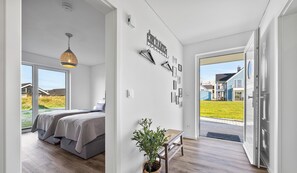 Une chambre moderne avec un grand lit, un luminaire suspendu et une vue sur l’extérieur.