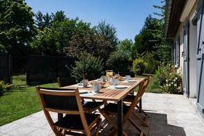 An outdoor dining area with a wooden table and chairs, surrounded by greenery and a house. - By the canal - Pets allowed - 3 bedrooms and an enclosed garden (Aÿ-Champagne)