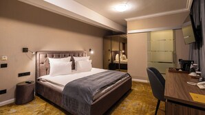 A hotel room with a bed, a desk with a telephone, a chair, a mirror, and a wardrobe. - Hotel Brilliant Plaza (Zalău)