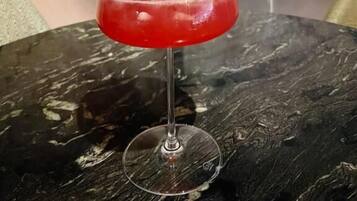 A cocktail with a garnish on a glass, placed on a table with a marble-like surface.