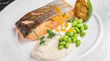 A plate with grilled salmon, a slice of lime, and a side of green beans.