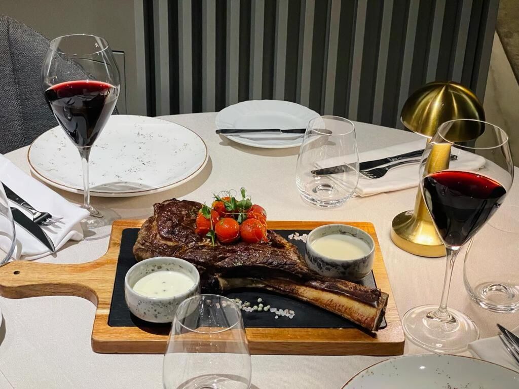 Une table à manger dressée avec un steak, des verres à vin et une bougie.