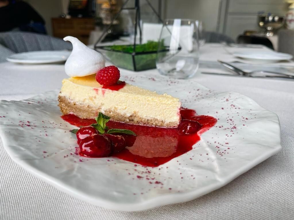 A dessert on a white plate with a berry sauce and a dollop of cream.