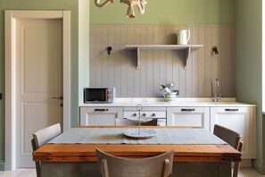 A kitchen with a wooden table, chairs, a microwave, a sink, and a shelf above the counter. - Luxury and Design in the Center of Milan, Stazione Garibaldi Brera (Milano)