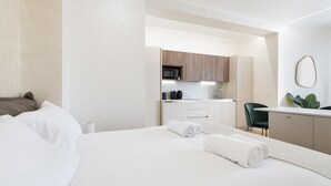 Habitación de hotel con cama, escritorio, silla y kitchenette.