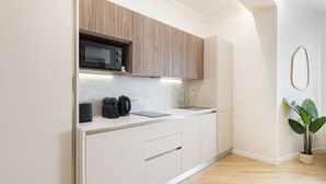 Una cocina moderna con armarios de madera, microondas integrado y encimera de mármol.