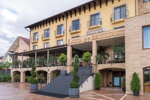 Un hotel con varios balcones, una entrada cubierta y una escalera que conduce a la entrada.
