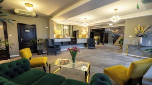 A hotel lobby with green and yellow seating, a reception desk, and a staircase leading to another floor. - Aria by Brilliant (Zalău)