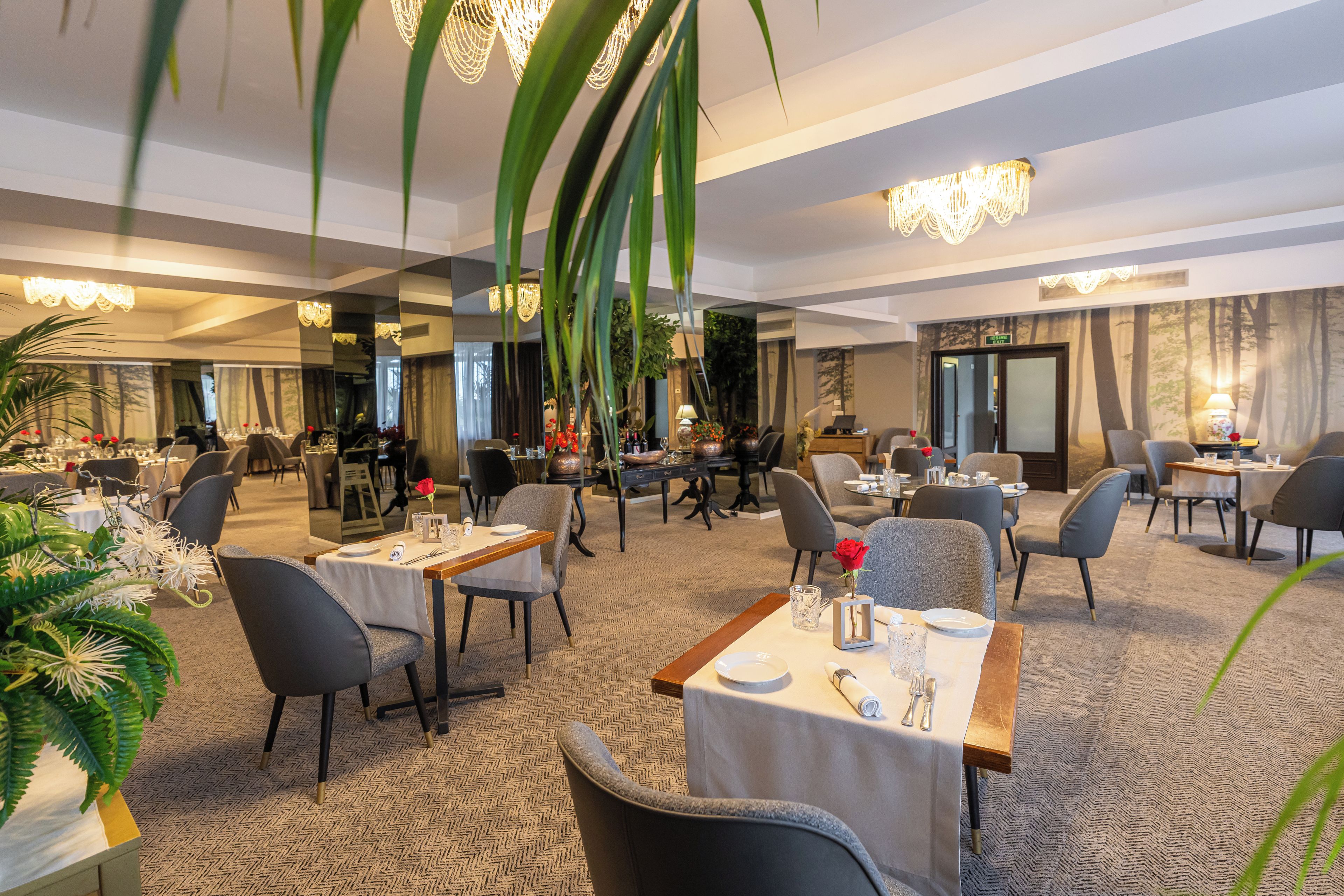 Espaço de refeições de hotel com várias mesas, cadeiras e piso coberto por carpete.