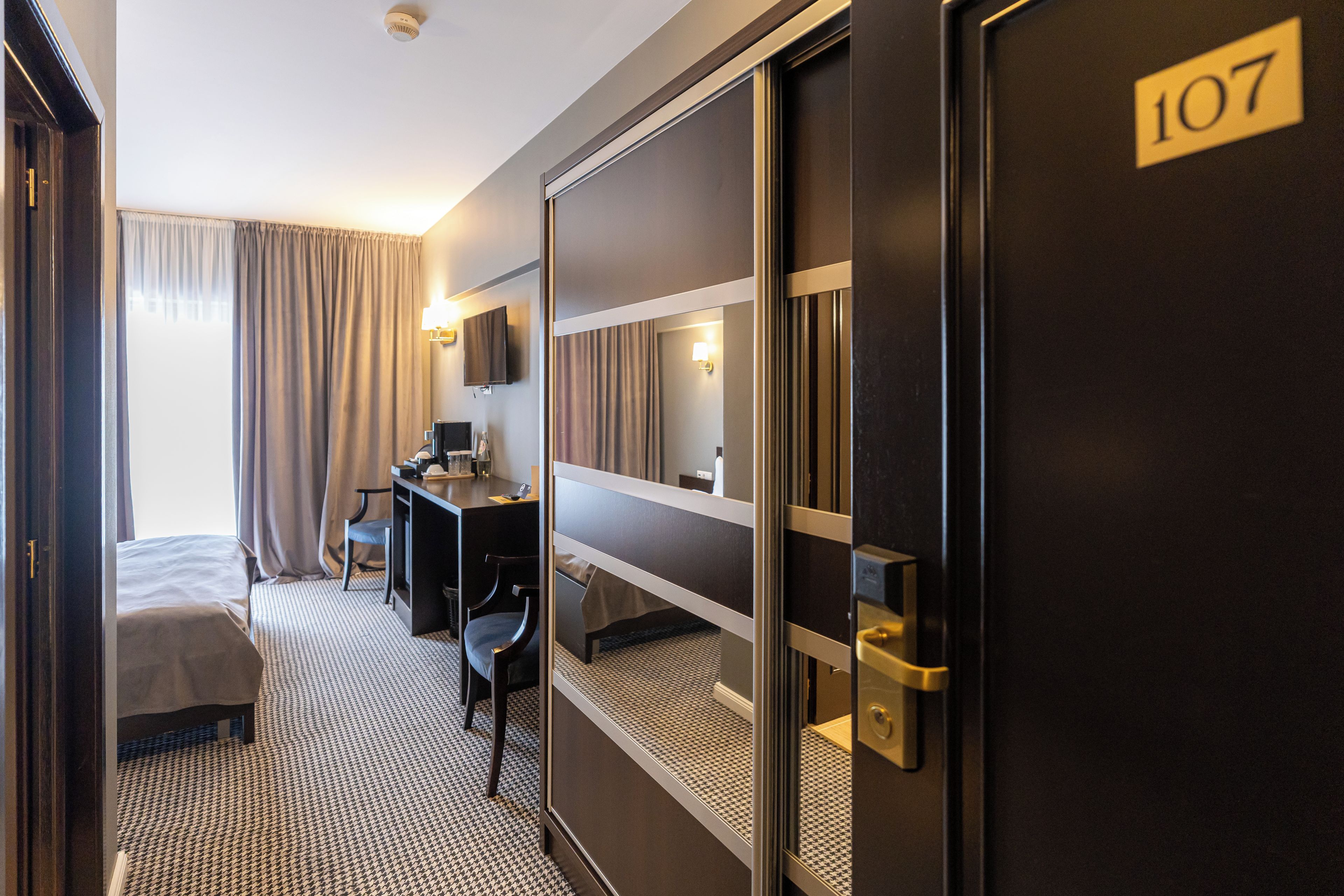 A hotel room with a bed, desk, chair, and a television.