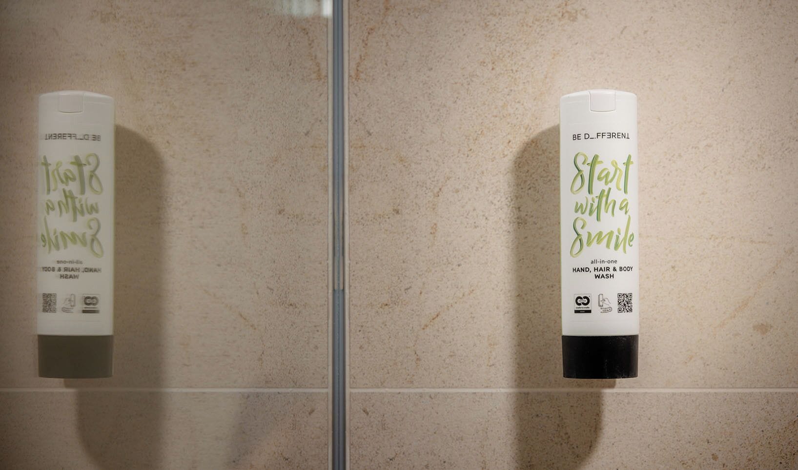 Two hand sanitizer dispensers mounted on a tiled wall.