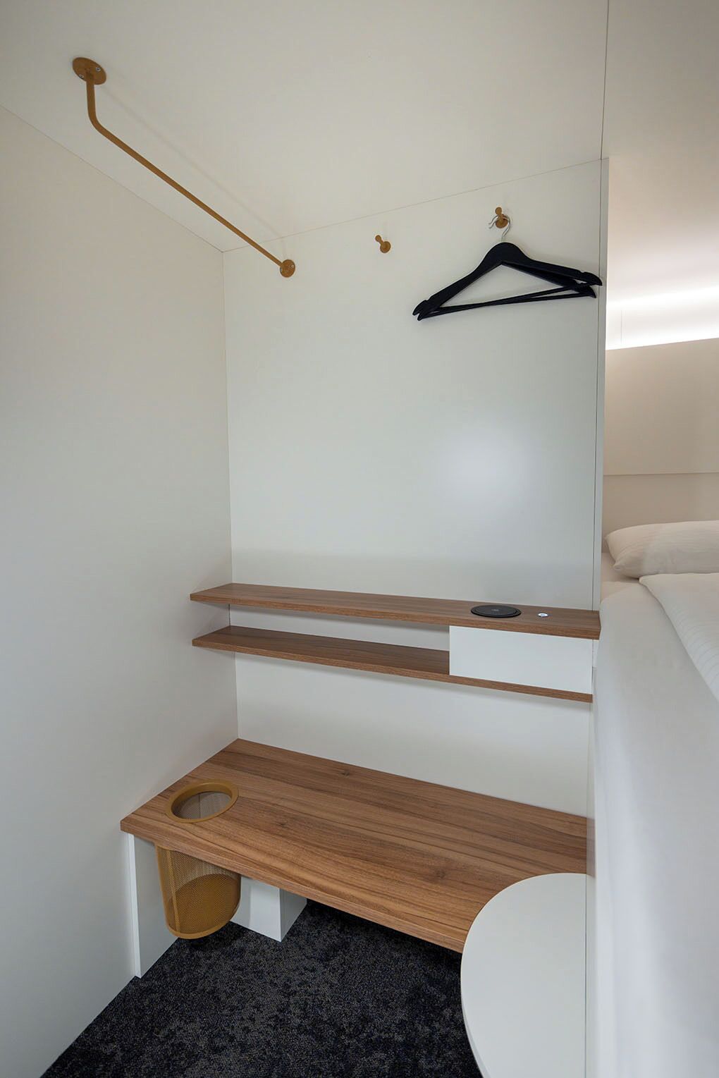 Un baño pequeño con inodoro, repisa de madera, perchero y barra para toallas.