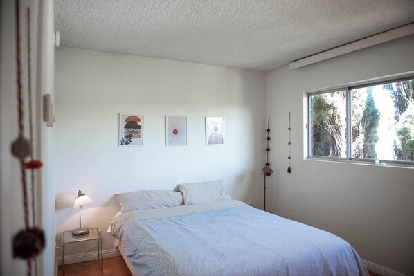 Un dormitorio con cama, mesita de noche con lámpara y decoración en la pared.