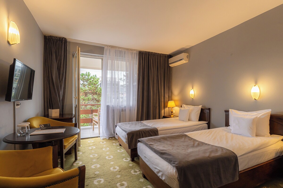 Une chambre d’hôtel avec deux lits, un bureau, une chaise, une télévision et un appareil de climatisation.