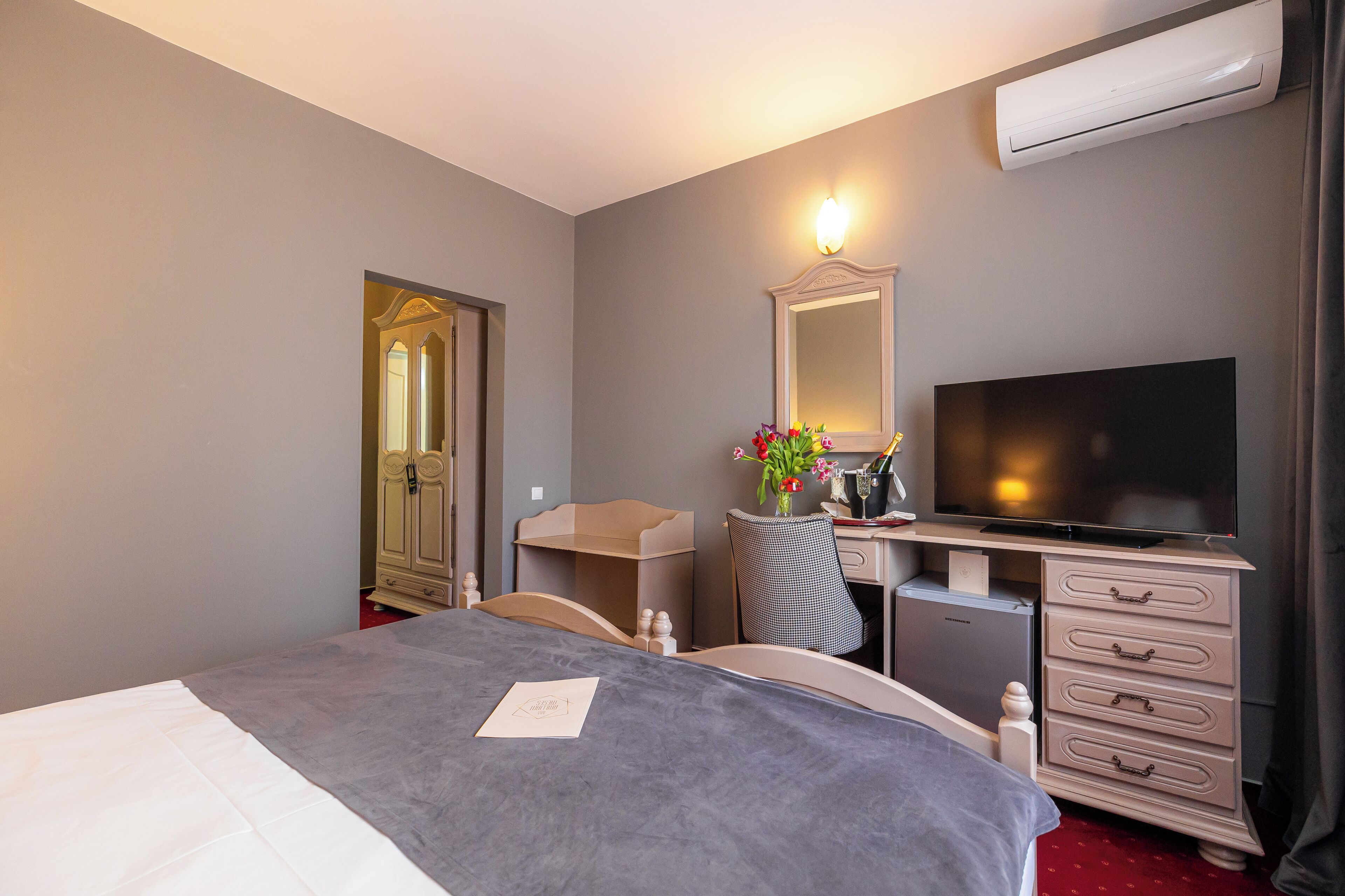Ein Hotelzimmer mit einem Bett, einem Schreibtisch, einem Fernseher, einem Schminktisch und einer Klimaanlage.