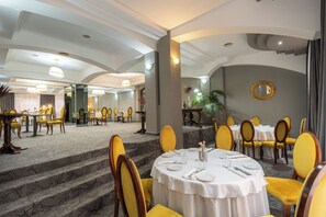 Un comedor de hotel con mesas redondas, sillas amarillas y una escalera de mármol.
