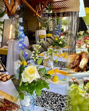 Un espace repas avec des tables dressées pour le repas, agrémenté de compositions florales et d’une variété de plats.