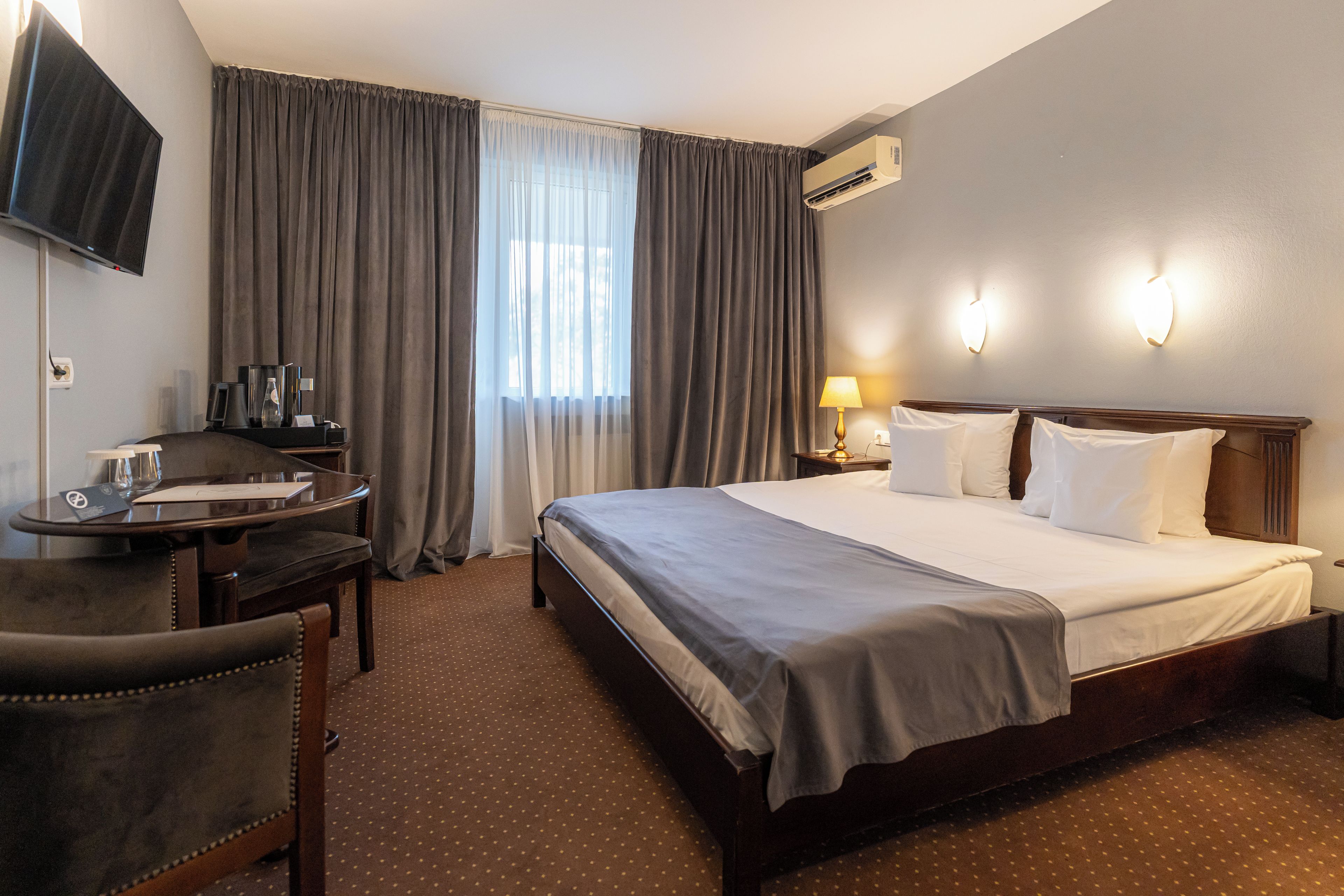 Une chambre d’hôtel équipée d’un lit, d’un bureau, d’une chaise, d’une télévision et d’un appareil de climatisation.