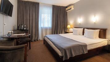 Une chambre d’hôtel équipée d’un lit, d’un bureau, d’une chaise, d’une télévision et d’un appareil de climatisation.