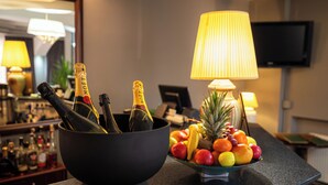 A bar area with a black bowl containing champagne bottles and a fruit bowl with various fruits.
