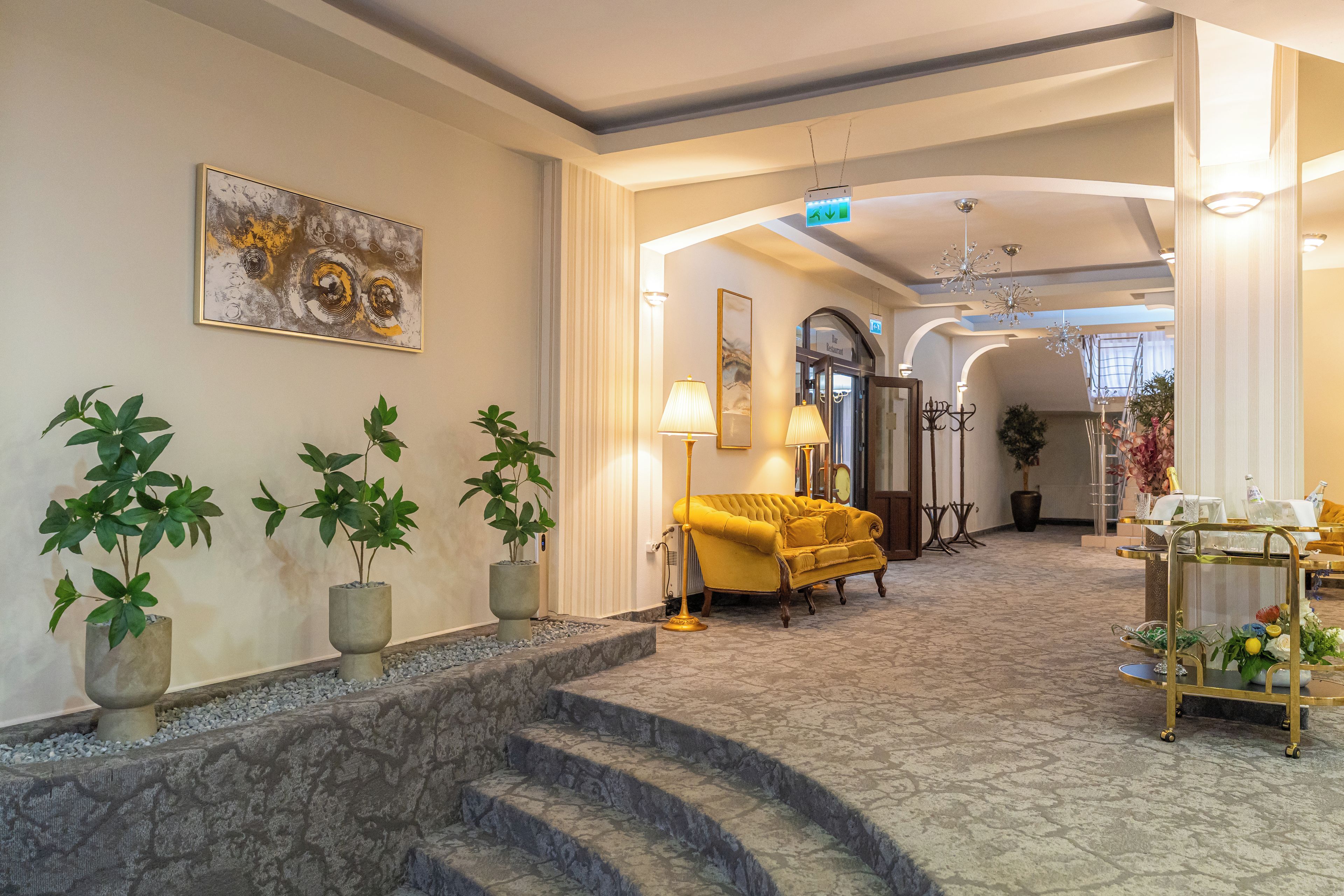 A hotel lobby with a marble staircase, a yellow sofa, and potted plants.