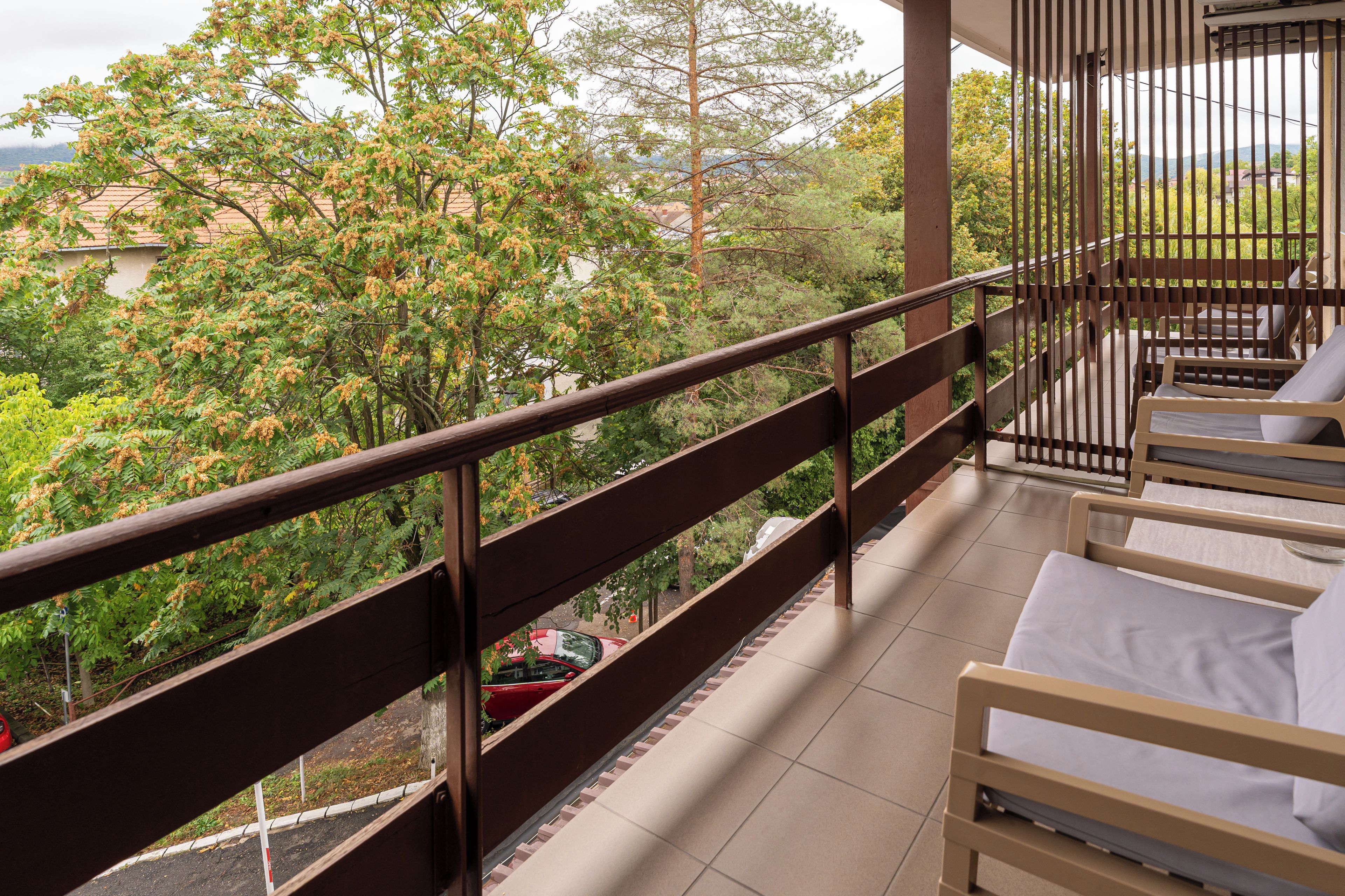 A balcony with a view of trees and a distant landscape.
