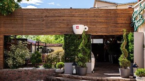 A building with a wooden facade, a large white cup-shaped structure, and potted plants.