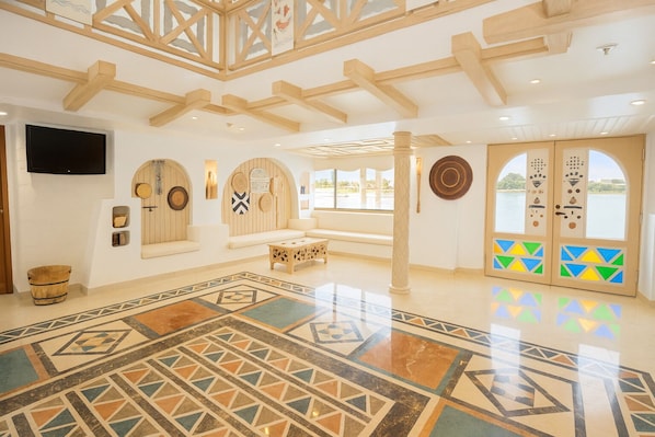 A spacious lobby with a high ceiling, a large seating area, a patterned floor, and a view of the outdoors.