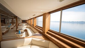 A modern interior with a long seating area along a large window overlooking a body of water. - Nile Cruise Majesty every Monday from Aswan 3 nights and every Thursday from Luxor 4 nights (Aswan)