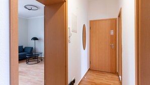 Ein Korridor mit Holzboden, einem runden Spiegel an der Wand und einer Tür mit einem Schild.