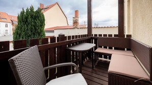 Ein überdachter Außenbereich mit Korbmöbeln und Blick auf angrenzende Gebäude.
