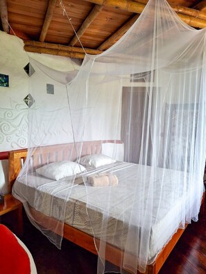 A bed with a mosquito net, wooden headboard, and pillows. - Paradiselodge - Poolvilla - next to Nauyaca (Platanillo de Baru)