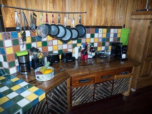 A kitchen with a wooden countertop, hanging pots, a coffee maker, and a fruit bowl. - Paradiselodge - Poolvilla - next to Nauyaca (Platanillo de Baru)