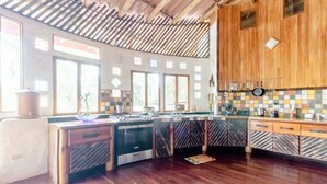 A kitchen with wooden cabinets, a stove, and a tiled backsplash. - Paradiselodge - Poolvilla - next to Nauyaca (Platanillo de Baru)