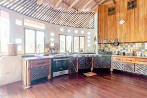 A kitchen with wooden cabinets, a stove, and a tiled backsplash. - Paradiselodge - Poolvilla - next to Nauyaca (Platanillo de Baru)