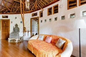A room with a wooden ceiling, a Buddha statue, a bed with patterned bedding, and a wall with framed pictures. - Paradiselodge - Poolvilla - next to Nauyaca (Platanillo de Baru)