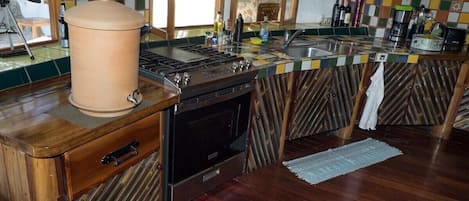 A kitchen with a wooden countertop, a stove, and a sink.