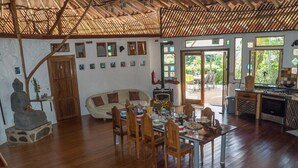 A spacious living area with a wooden dining table set for a meal, a sofa, and a Buddha statue. - Paradiselodge - Poolvilla - next to Nauyaca (Platanillo de Baru)
