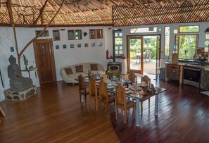 A spacious living area with a wooden dining table set for a meal, a sofa, and a Buddha statue. - Paradiselodge - Poolvilla - next to Nauyaca (Platanillo de Baru)