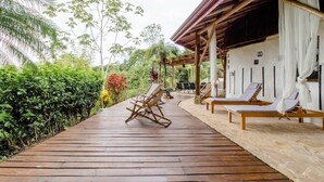 A wooden deck with lounge chairs and a covered area with white curtains. - Paradiselodge - Poolvilla - next to Nauyaca (Platanillo de Baru)