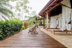 A wooden deck with lounge chairs and a covered area with white curtains. - Paradiselodge - Poolvilla - next to Nauyaca (Platanillo de Baru)