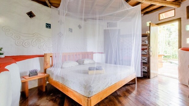 A wooden bed with a canopy, a small bedside table, and a bench. - Paradiselodge - Poolvilla - next to Nauyaca (Platanillo de Baru)