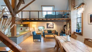 A spacious loft-style living area with a high ceiling, exposed wooden beams, a dining table, and a cozy seating area. - Rural Private Loft (Meerkerk)