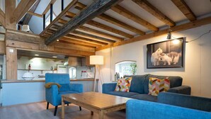 A cozy living room with a wooden ceiling, a sofa, a blue armchair, and a wooden coffee table. - Rural Private Loft (Meerkerk)
