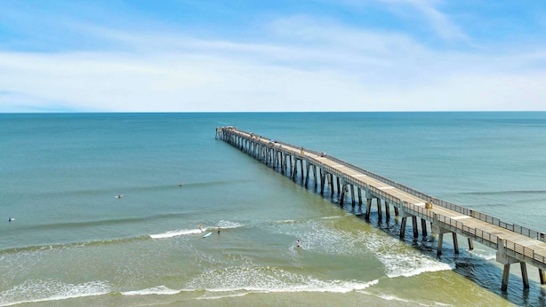 A long pier extending into calm waters with clear skies.