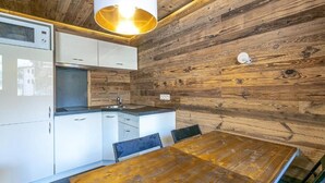 Une cuisine moderne avec des meubles blancs, une table à manger en bois et un luminaire suspendu.