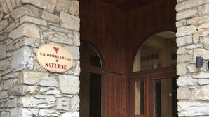 Une façade en pierre avec une porte en bois et une enseigne indiquant « Val d’Isère, Village de Saturne ».