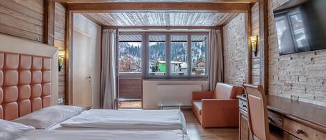 Una habitación de hotel con cama, escritorio, televisor y vista al exterior.